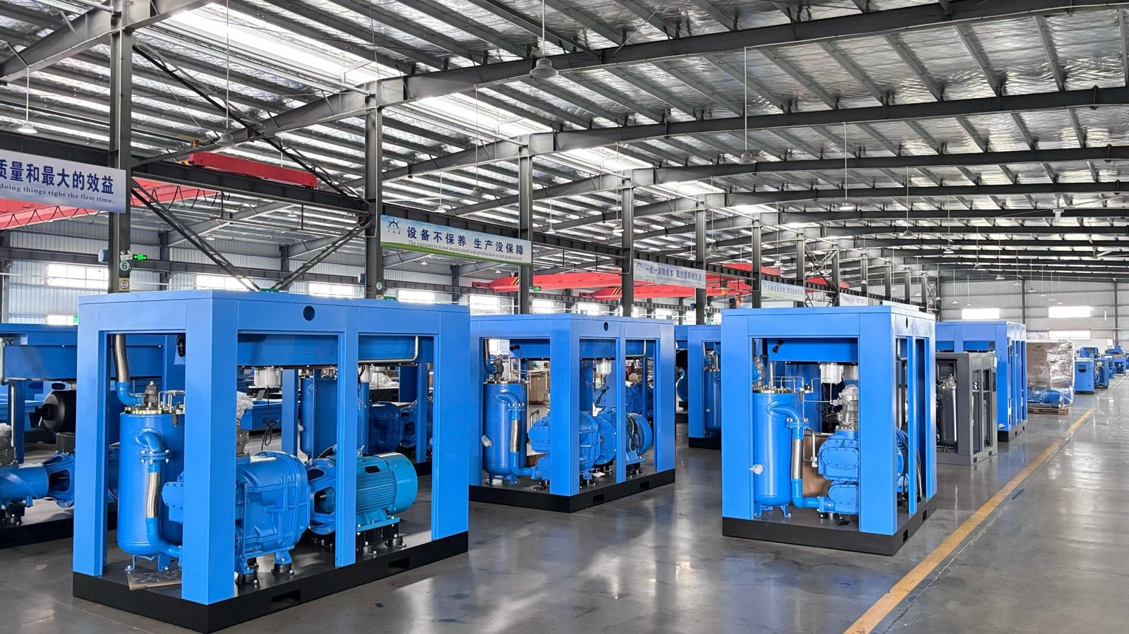 Large blue screw air compressors with open cabinets on the factory assembly line